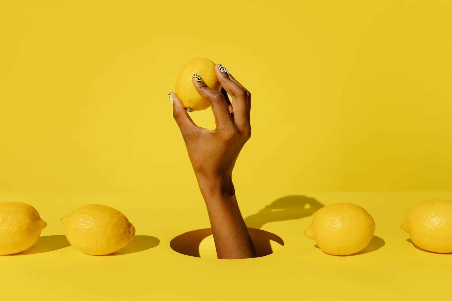 A hand holding a fresh lemon against a vivid yellow background, symbolizing fresh sensation and gradual buildup
