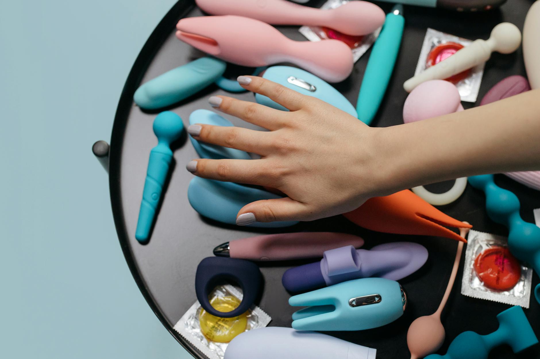 Woman holding a vibrator with art books nearby, symbolizing the blend of sensuality and emotional depth