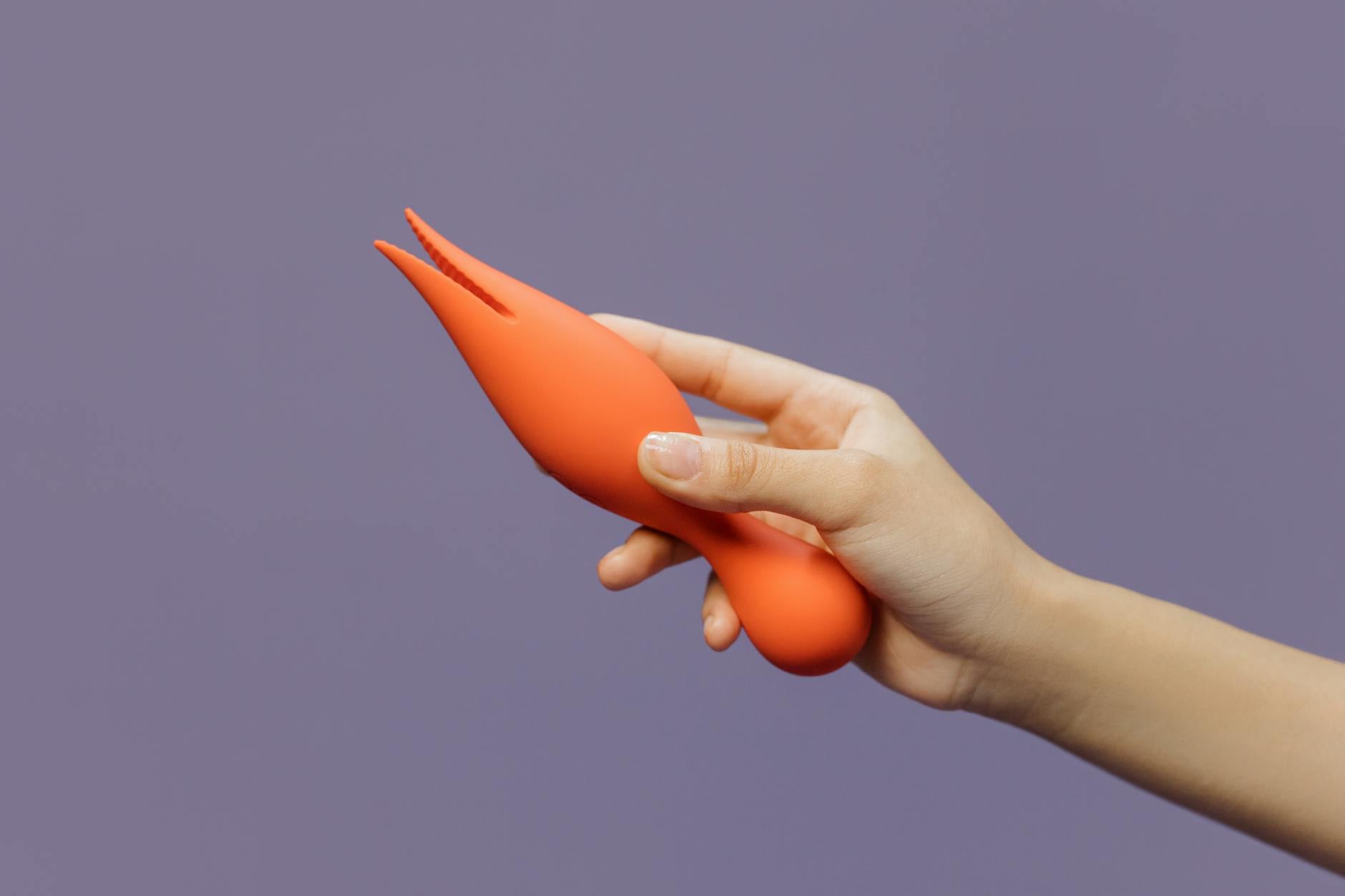 A hand holding a lemon vibrator against a purple backdrop, showcasing intimate sensuality