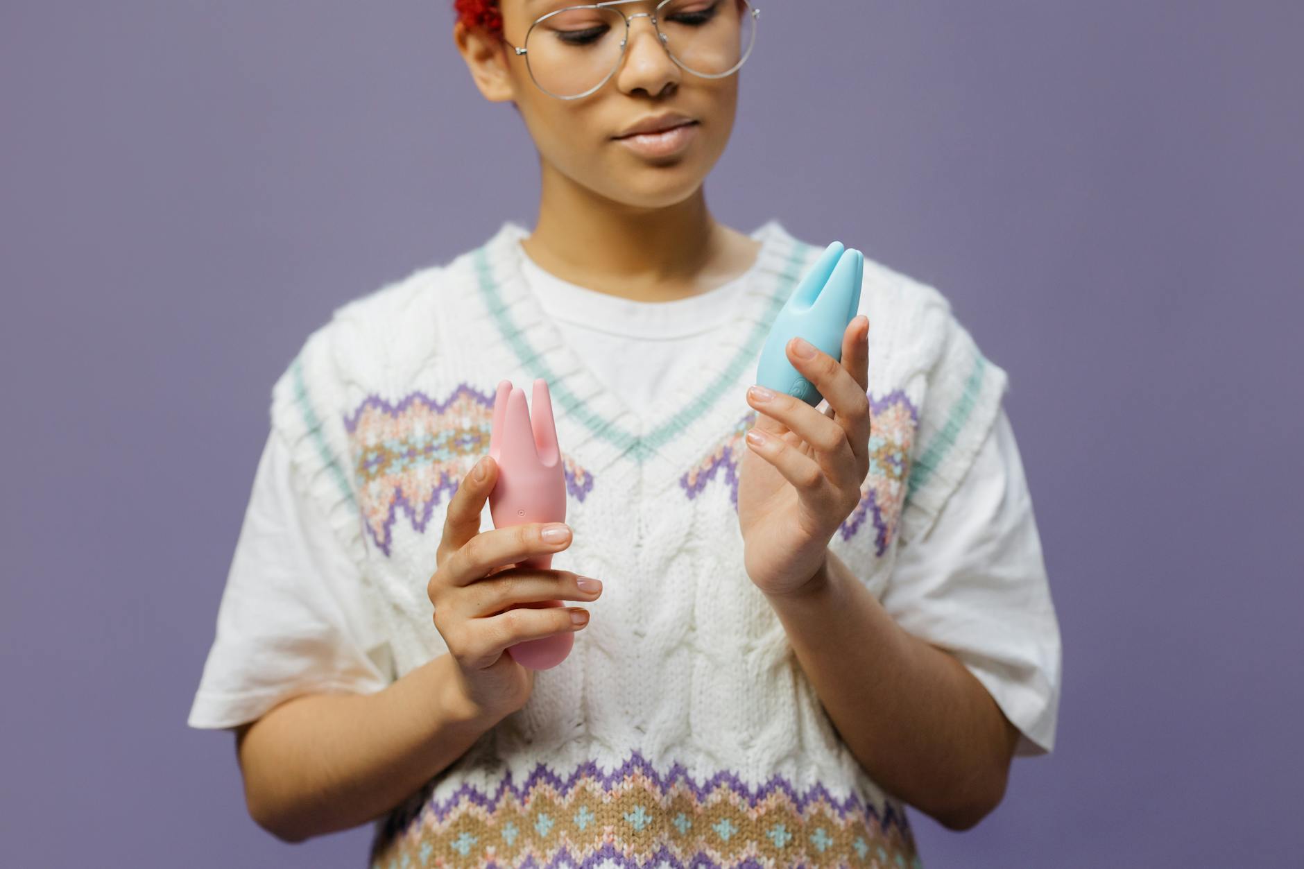 Woman holding colorful vibrators in a contemplative moment of self-pleasure and personal intimacy.